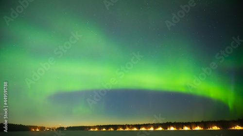 A green colour Aurora borealis panorama on the starry night sky over a city. Aurora Borealis over Swedish lake Islands. Northern Sweden.