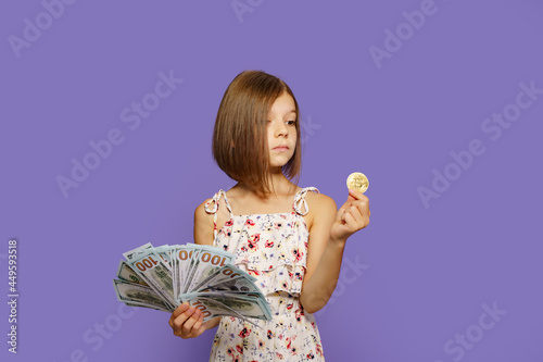 Beautiful little girl holding virtual currency bitcoin and dollars perplexedly don't know what to choose to invest future photo