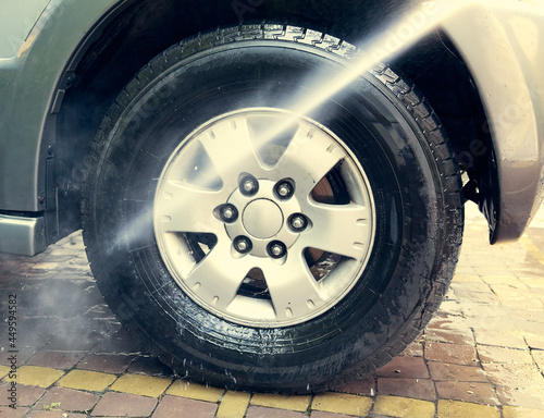 Jet washes a car wheel in the yard of  house. Odessaa Ukraine  colored  full frame  natural light.