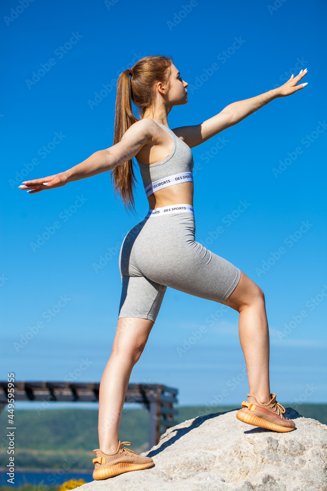 Young beautiful blonde woman in sports uniform is engaged in fitness outdoors Young beautiful blonde woman in sports uniform is engaged in fitness outdoors