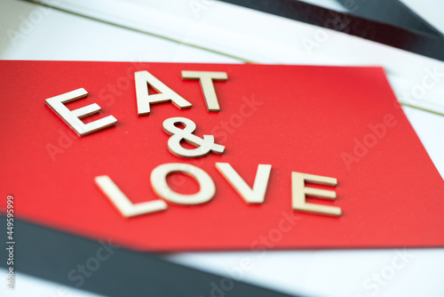 the expression "eat & love" in san serif capital letters on a red background - close up using a macro lens - shallow depth of field (subjective focusing)