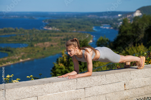 Young beautiful blonde woman in sports uniform is engaged in fitness outdoors