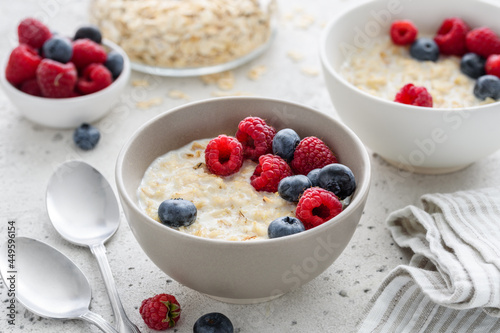 Milk oatmeal porridge with fresh raspberries and blueberries. Healthy breakfast. Vegetarian food. Selective focus 