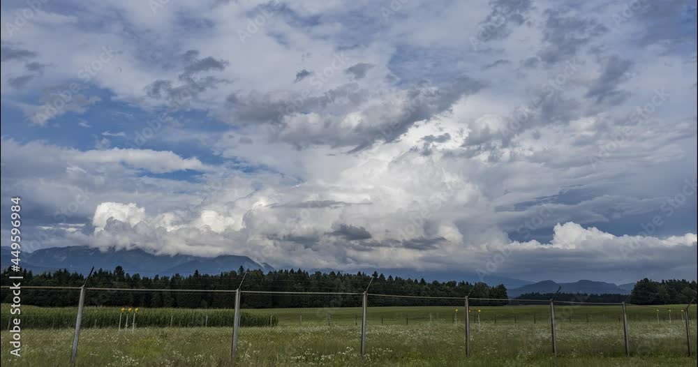 Time lapse of clouds moving over meadows, forest and mountains. Ljubljana airport fence in the foreground. Countryside grassland field. Zoom in Time lapse of clouds moving over meadows, forest and mountains. Ljubljana airport fence in the foreground. Countryside grassland field. Zoom in