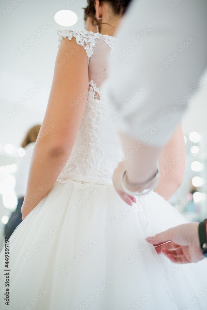 the bride is laced up with a corset on her white dress