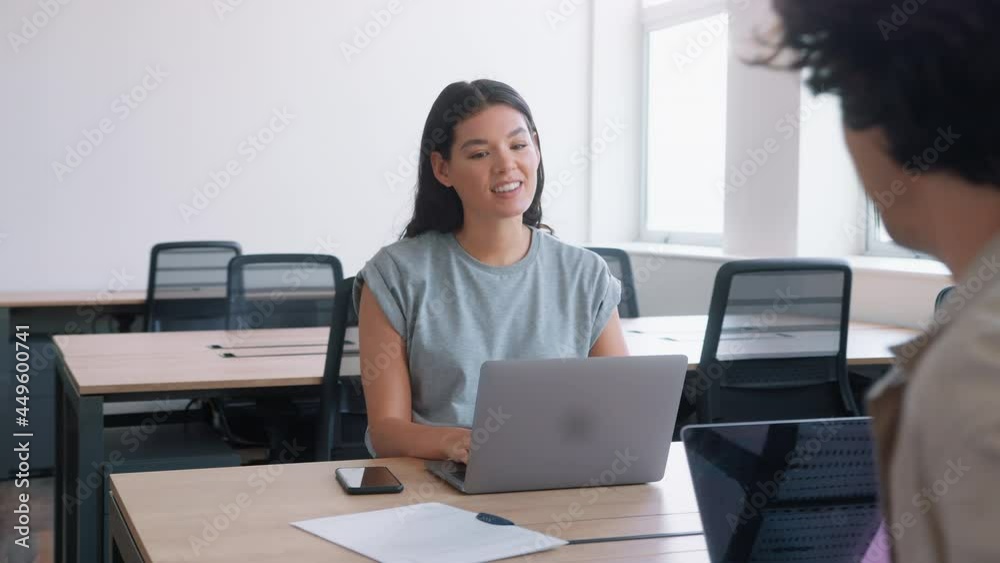 Casually dressed young man and woman working on laptops at desks in modern open plan office looking at data on digital tablet in slow motion Casually dressed young man and woman working on laptops at desks in modern open plan office looking at data on digital tablet in slow motion