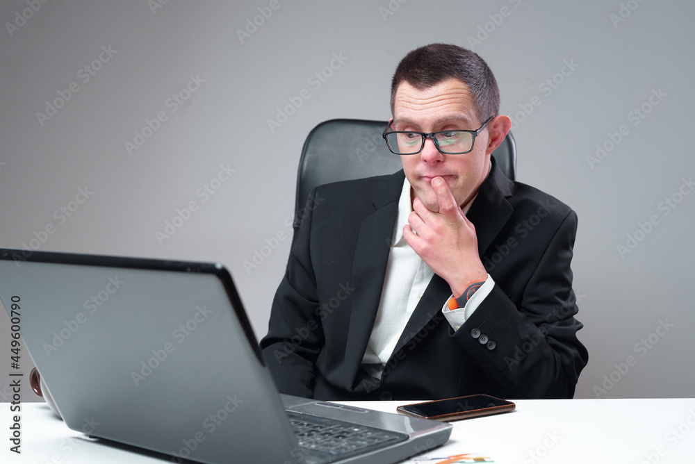 Social inclusion: Down syndrome businessman working on his laptop in his office Social inclusion: Down syndrome businessman working on his laptop in his office