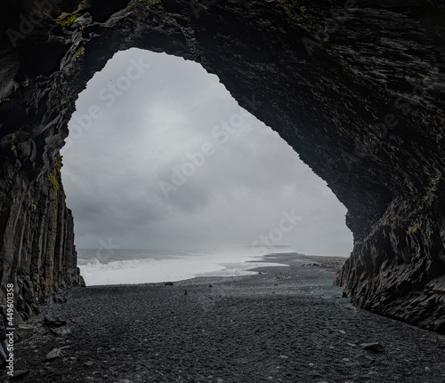 Panoramic view  of Reynisfjara beach cave in Iceland with big basalt pillars and rocky beach. Cold windi place at the beach with big waves. photo