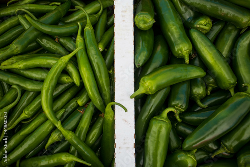 Two varieties of organic green chili peppers - Jalapeño and Serrano, in a box at a market in California