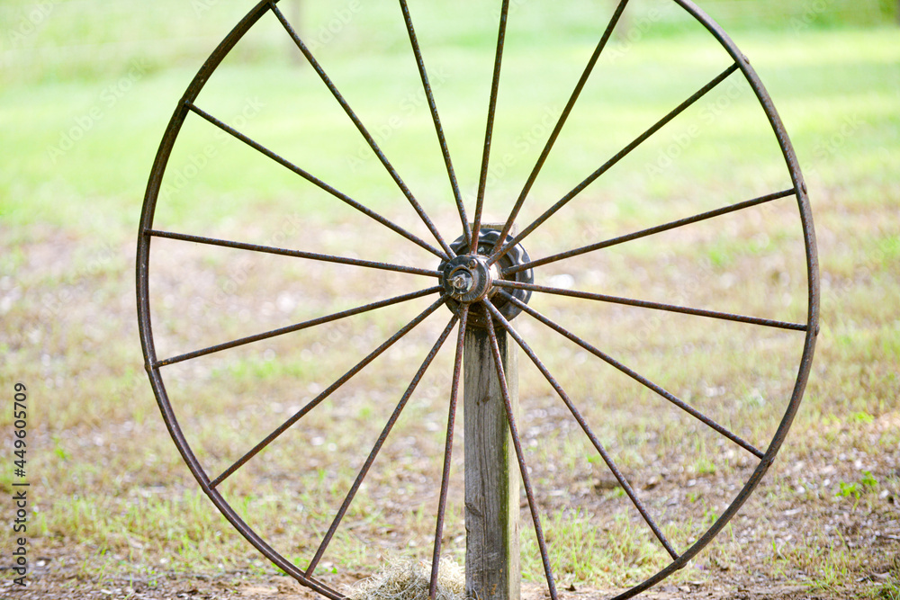 Old rusted wagon wheel rim spoke attached to wood as yard decor