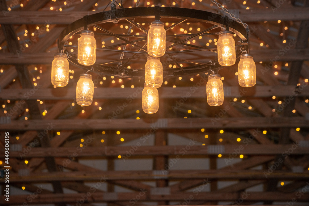 Amazing wagon wheel lamp with mason jar scavos hanging from wood beam barn ceiling