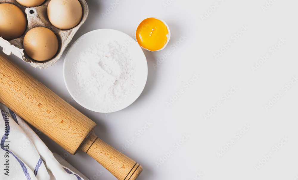 Top view of baking and cooking ingredients. Flour and eggs, rolling pin on grey background. Bakery background frame. Copy space place. Flat lay. Top view of baking and cooking ingredients. Flour and eggs, rolling pin on grey background. Bakery background frame. Copy space place. Flat lay.