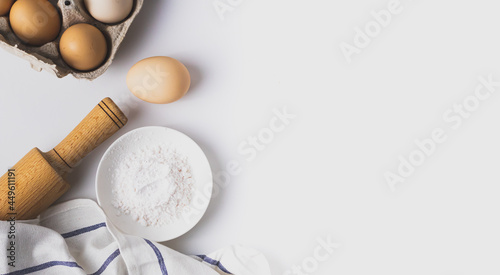 Top view of baking and cooking ingredients. Flour and eggs, rolling pin on grey background. Bakery background frame. Copy space place. Flat lay.