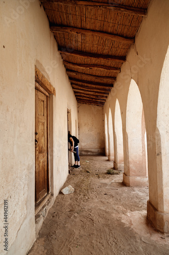 Tourist woman spies through a door of an abandoned adobe building in Salta  Argentina