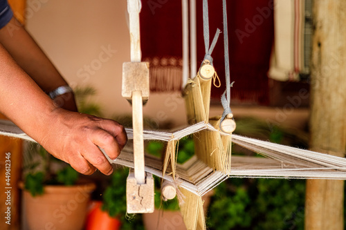 Closeup of hand of a craftsman weaving a tapestry on a wooden loom photo