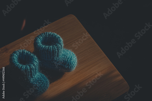 A pair of blue booties for a small child. Early morning, light from the window.