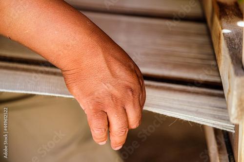 Closeup of hand of a craftsman weaving a tapestry on a wooden loom photo