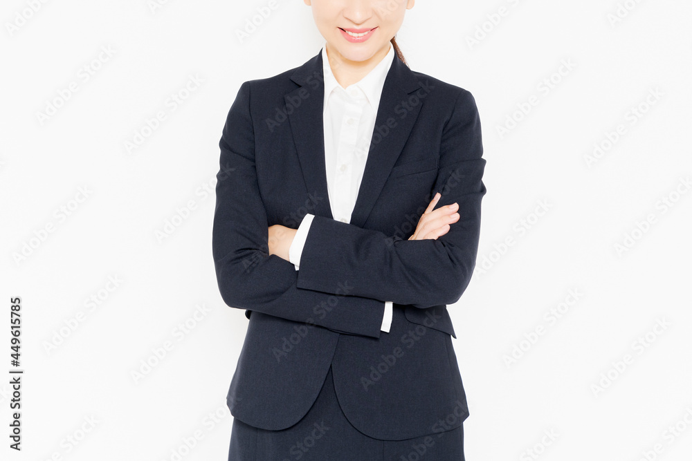 白背景の前に立って、腕組みをしている、スーツを着たビジネスウーマン