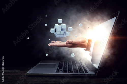 фотографія Man`s hand in a laptop and cubes levitating above