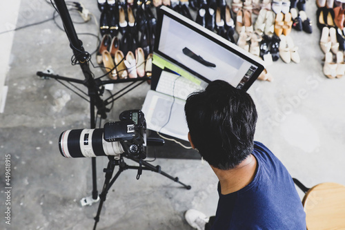 Male photographer working with monitor, camera, tripod and light stand 