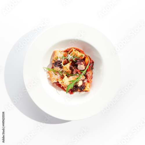 Cannelloni pasta with seafood and Parmesan cheese. Lasagna cannelloni pasta stuffed with tomato sauce and fried octopus. Italian pasta in white plate isolated on white background .