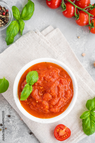 Fotografie Traditional Italian marinara sauce in a bowl on a concrete background with spices and ingredients