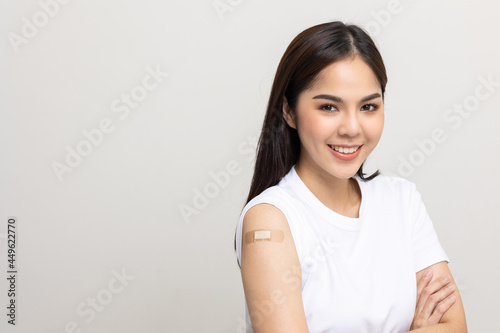 Vaccination. Young beautiful asian woman getting a vaccine protection the coronavirus. Smiling happy female showing arm with bandage after receiving vaccination. On isolated white background.