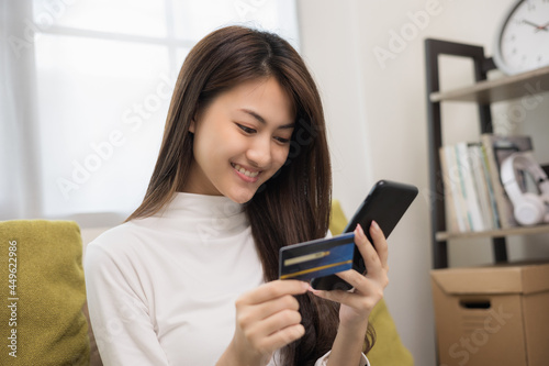 Shopping online. Young asian teenage girl input the serial number of credit card to smartphone for shopping payment. Buy item online delivery at home. Smiling female feeling happy.