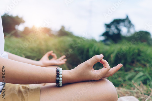 Woman practicing yoga lesson, breathing, meditating exercise, outdoor in grass field. Well being, wellness.