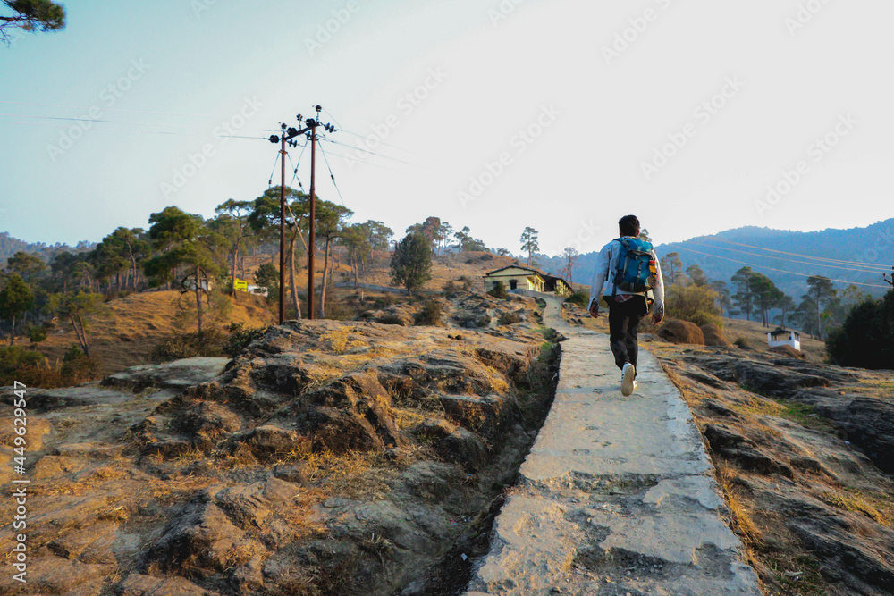 Obraz premium a man walking on a path , mountain hike , house in background 
