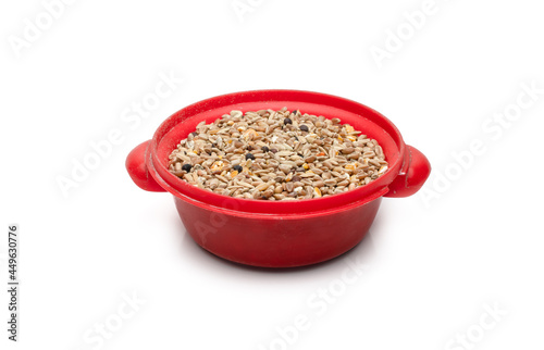 Mixing pigeon food or various seeds on a small red toy bowl on an isolated white background