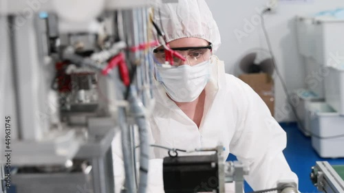 Engineer or technician in protective suite working on medical face mask machine production factory, Hygiene clean manufacturing concept
