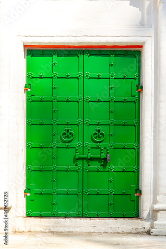 green antique iron door with lock on white brick wall background