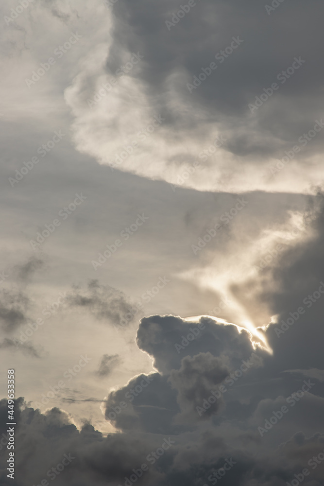 The sun shines through the clouds in the sunset sky with dramatic light. The shape of the clouds evokes imagination and creativity. They can be used as wallpapers that look amazing. Copy space, Select
