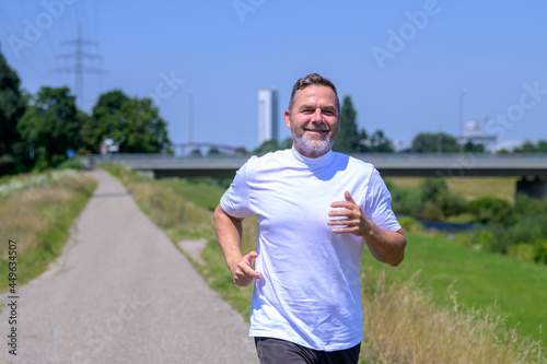Fit healthy senior man jogging along a footpath