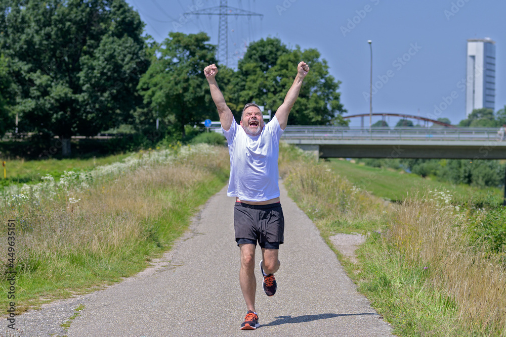 Joyful exubernat middle-aged man celebrating as he goes jogging