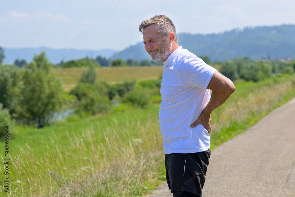 Middle-aged man grimacing as he clutches his lower back