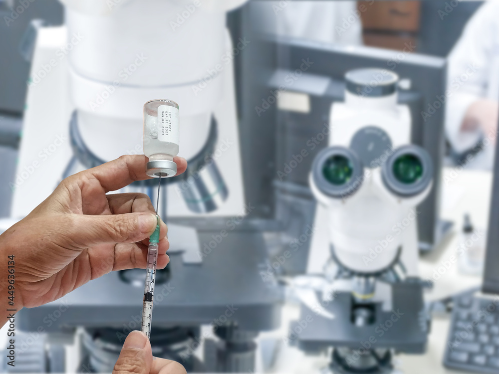 holds a syringe with a liquid vaccine in development laboratory holds a syringe with a liquid vaccine in development laboratory