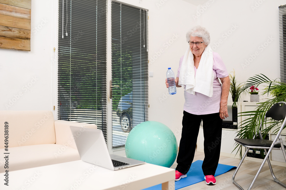 portrait of an active and dynamic senior woman doing sport fitness at home and holding mineral water bottle portrait of an active and dynamic senior woman doing sport fitness at home and holding mineral water bottle