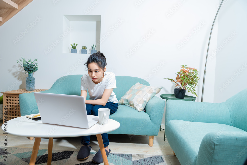 Young Asian woman holding notebook and smart phone while confirming work