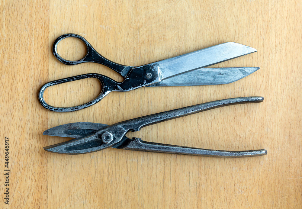Old tailor's scissors and metal shears isolated on a wooden background closeup Old tailor's scissors and metal shears isolated on a wooden background closeup
