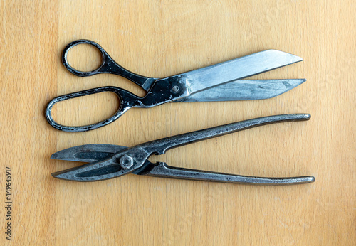 Old tailor's scissors and metal shears isolated on a wooden background closeup