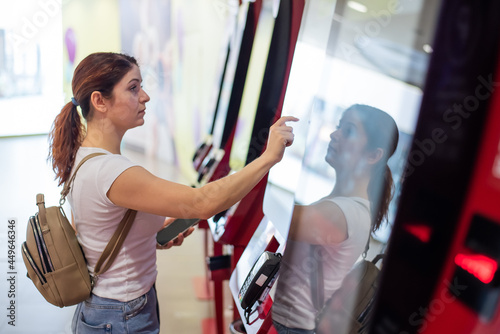 Caucasian woman buying cinema ticket at self-service box office. photo