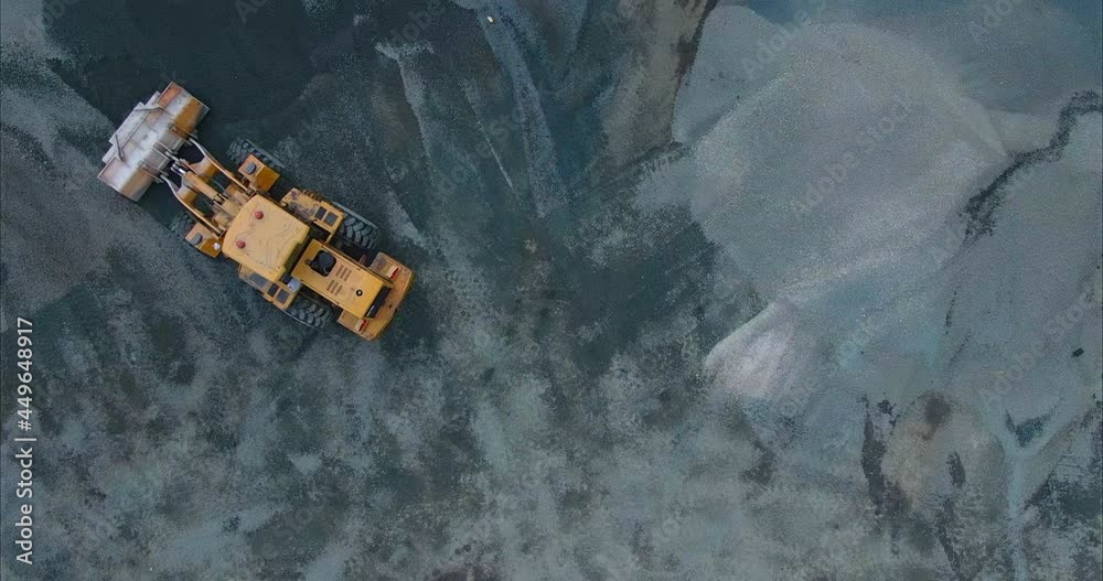 View from the copter, a large construction base with asphalt and rubble. Yellow loader picks up asphalt, mountains of asphalt and rubble in the bucket. 4k, ProRes View from the copter, a large construction base with asphalt and rubble. Yellow loader picks up asphalt, mountains of asphalt and rubble in the bucket. 4k, ProRes