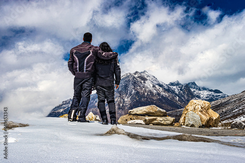 isolated young couple standing at mountain top and dramatic sky at day