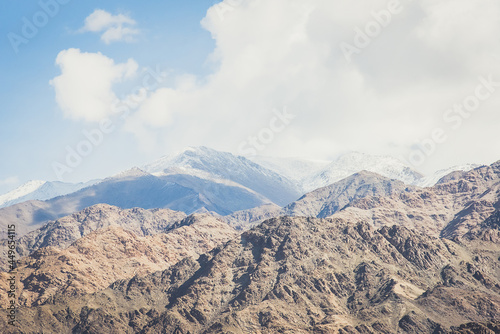 Beautiful panoramic view of a mountainside lit at the sunset period and also including of a snow found high up in the mountain peaks.