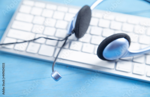 Customer service headset and computer keyboard on the blue background.