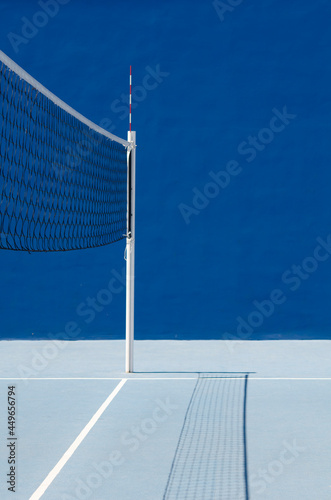 Blue sports playground. A place to play volleyball. Focus on the volleyball net with shadow. photo