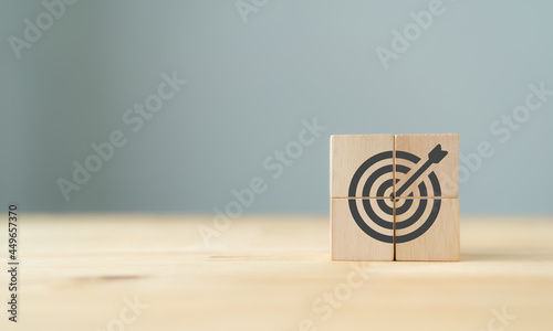 Business goal and success concept. Focus on a goal and achieve successful business. Initiation for planning to reach target. Darts target aim icon on wooden cubes with grey background. Copy space. 
