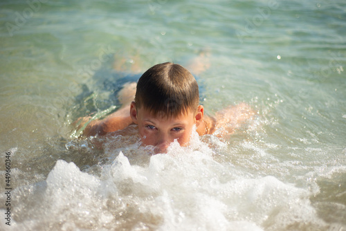 
The boy swims in the sea. Face in sea foam. Satisfied emotions. Pleasure